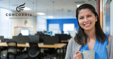 Smiling teacher drinking coffee with Concordia logo