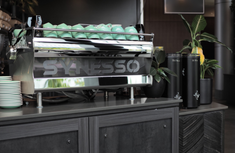 Synesso Hydra commercial espresso machine on counter with teal cups on top