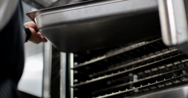 Hands taking sheet pan out of Southbend Impingement oven convection oven
