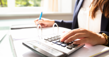Woman at desk with blue pen and calculator - restaurant labor costs