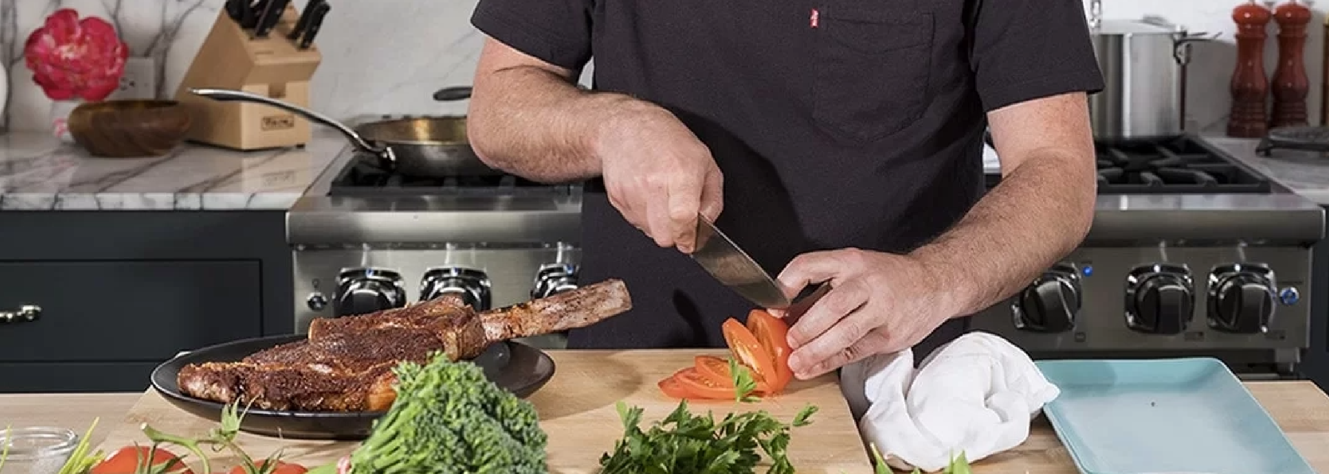 Chef slicing a tomato while steak rests