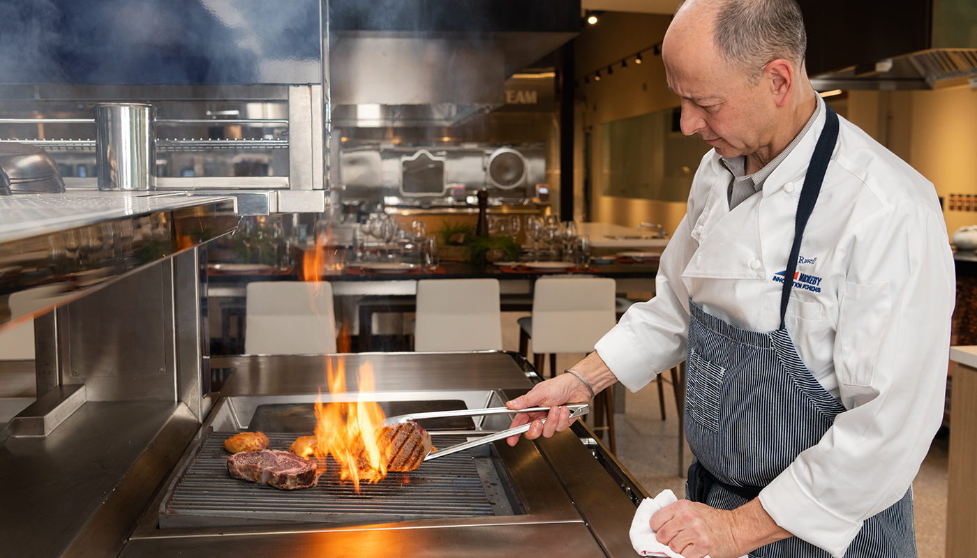 Chef Russel Scott cooking a steak with fire and grill