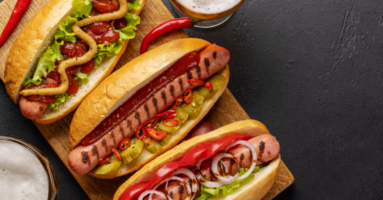 looking down on three hot dogs on a gray table
