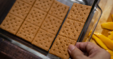 looking down at a hand snapping off a row of crackers inside a pan